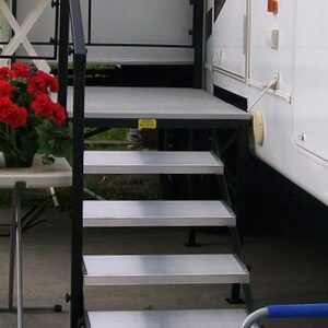 A cat sitting on top of steps in front of a camper.
