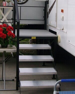 A cat sitting on top of steps in front of a camper.