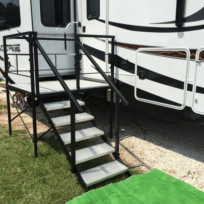 A black metal stair case leading to the front of a white rv.